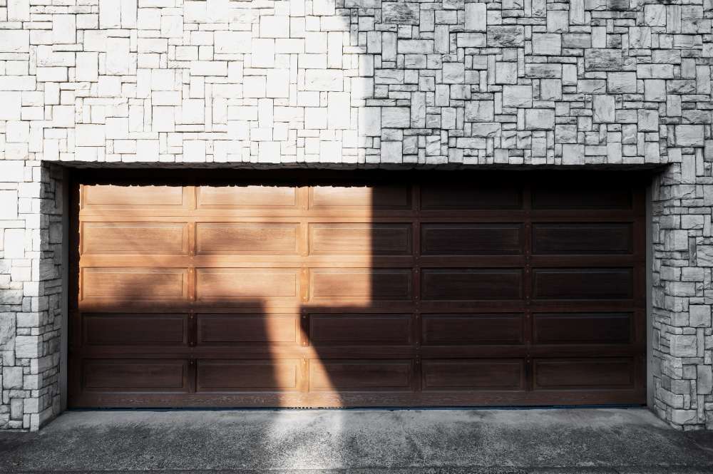 Wooden garage door below a stone wall, partially